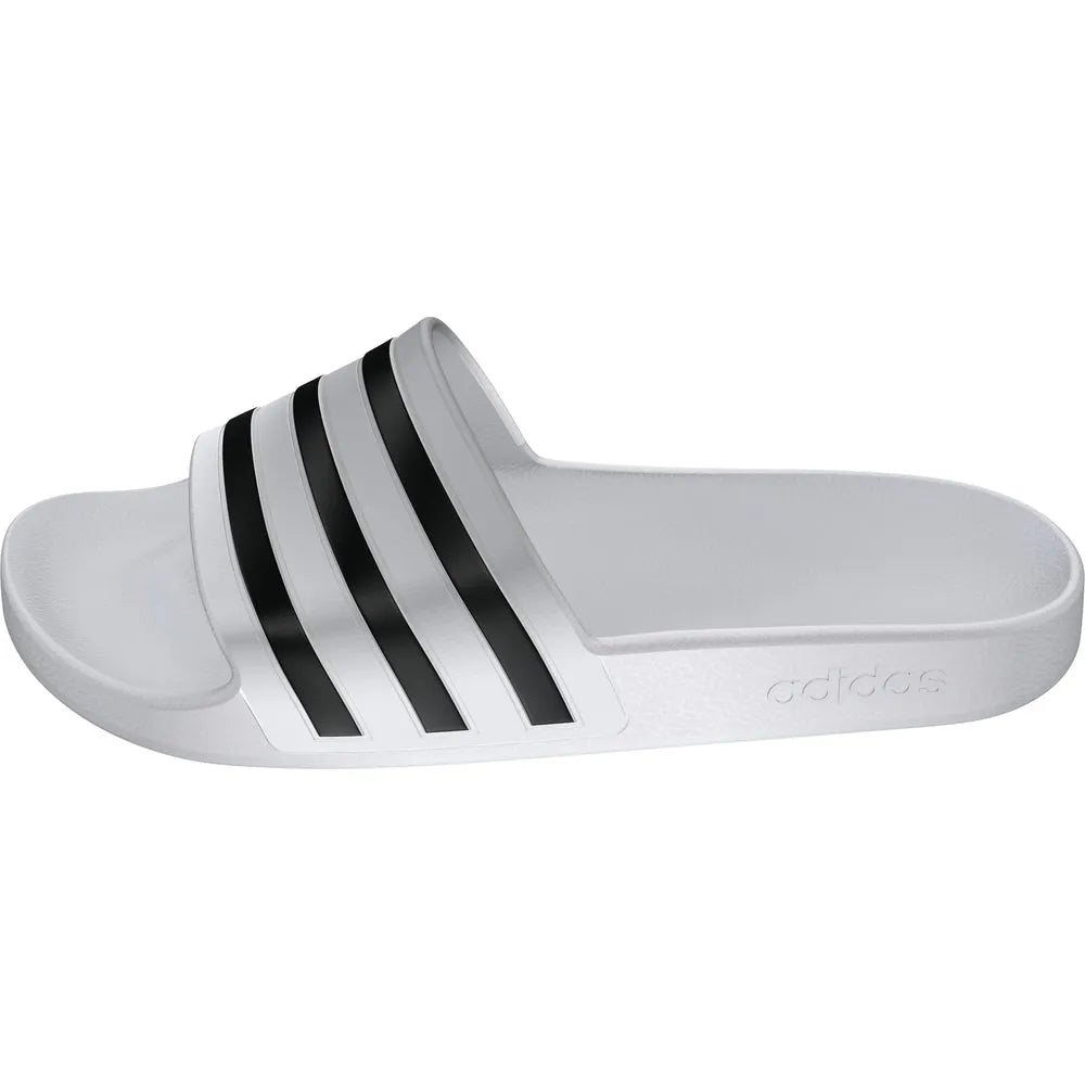 White Adidas Adilette Aqua slides on a tiled floor, showcasing sporty slide sandals with open toes and adjustable straps.