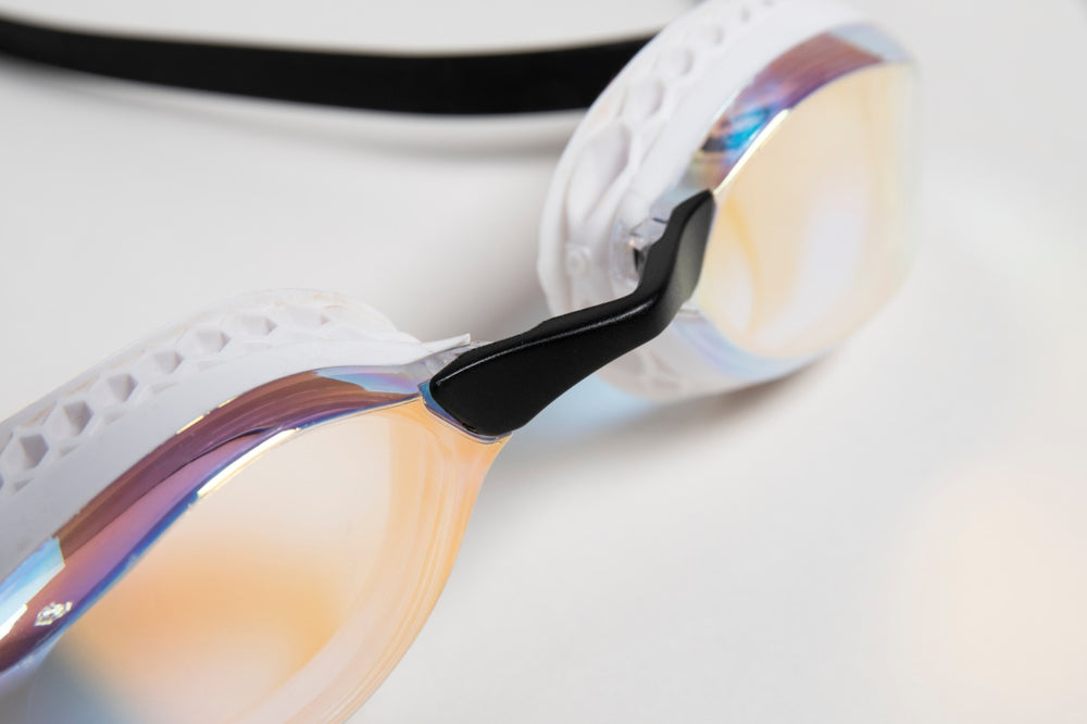 Arena Airspeed Mirror goggles in white and copper with tinted lenses and adjustable straps, designed for competitive swimming.