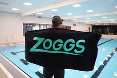 Zoggs swimming pool towel in black and turquoise, soft and absorbent, perfect for drying off after swimming.